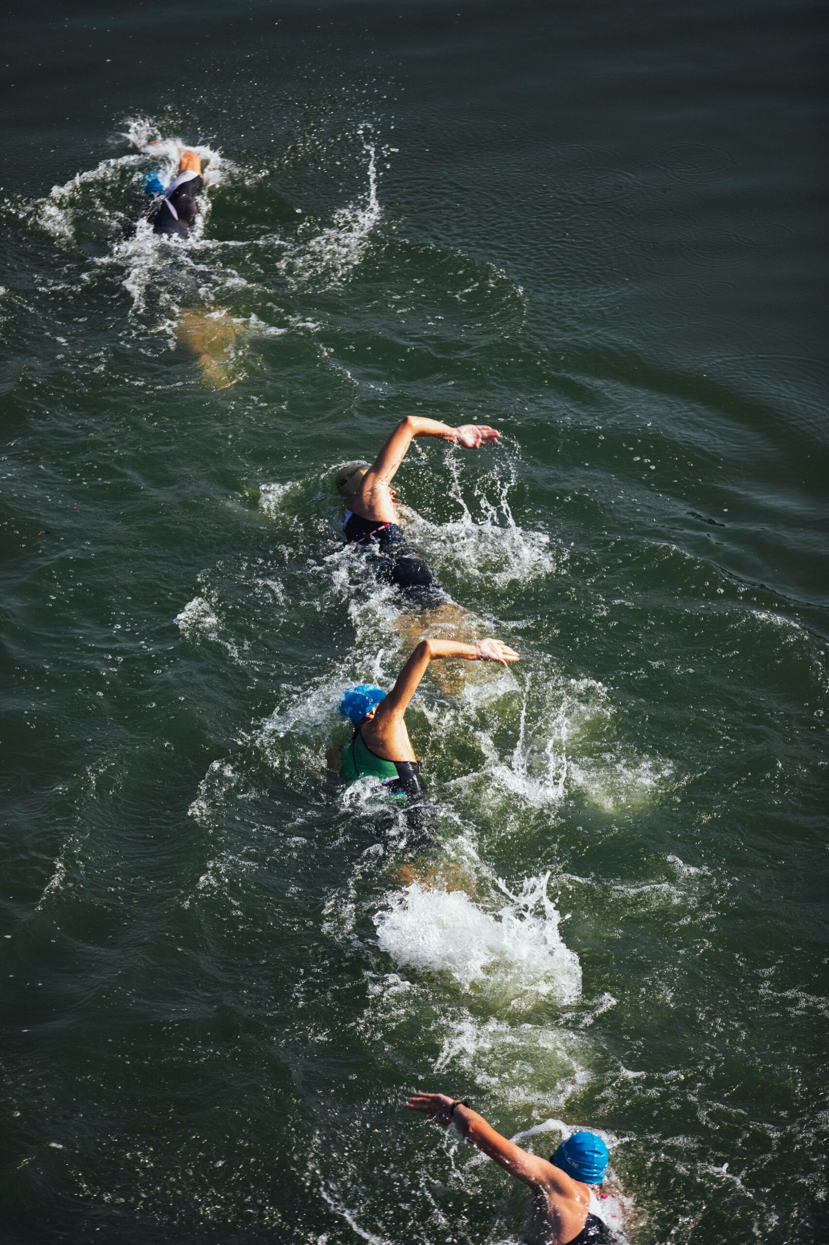 A group of swimmers in a line in open water. Photo by Markus Spiske.